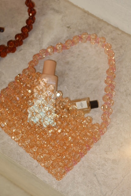 Lifestyle photo of peach sparkly bag by Kloopbags, perfect for beach clubs or dinner dates